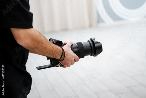 A videographer shoots a report at an event, a person holds a camera in his hands, a folding screen of equipment.