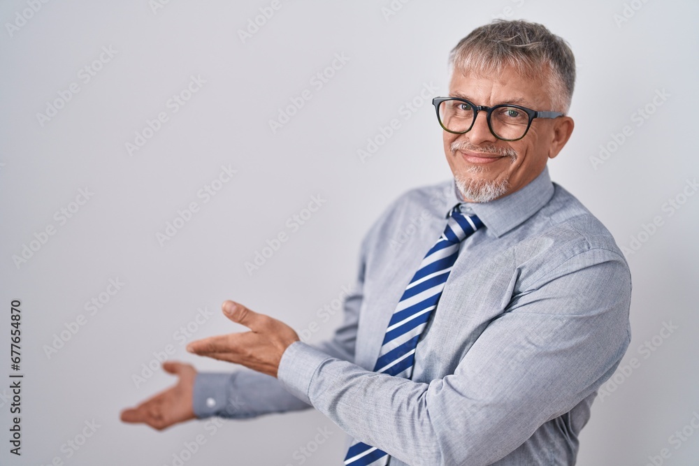 Hispanic business man with grey hair wearing glasses inviting to enter smiling natural with open hand Hispanic business man with grey hair wearing glasses inviting to enter smiling natural with open hand