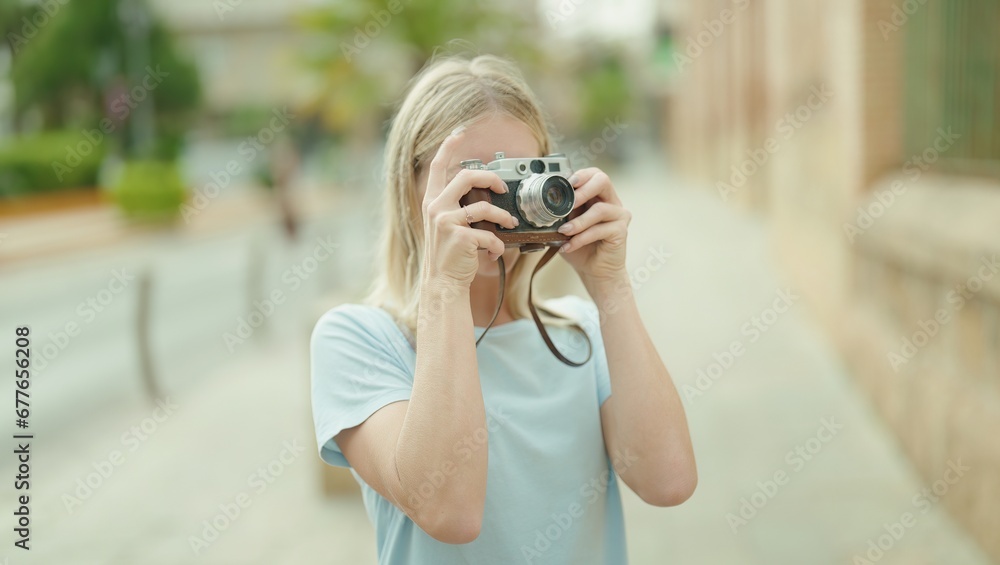 Young blonde woman tourist using vintage camera at street
