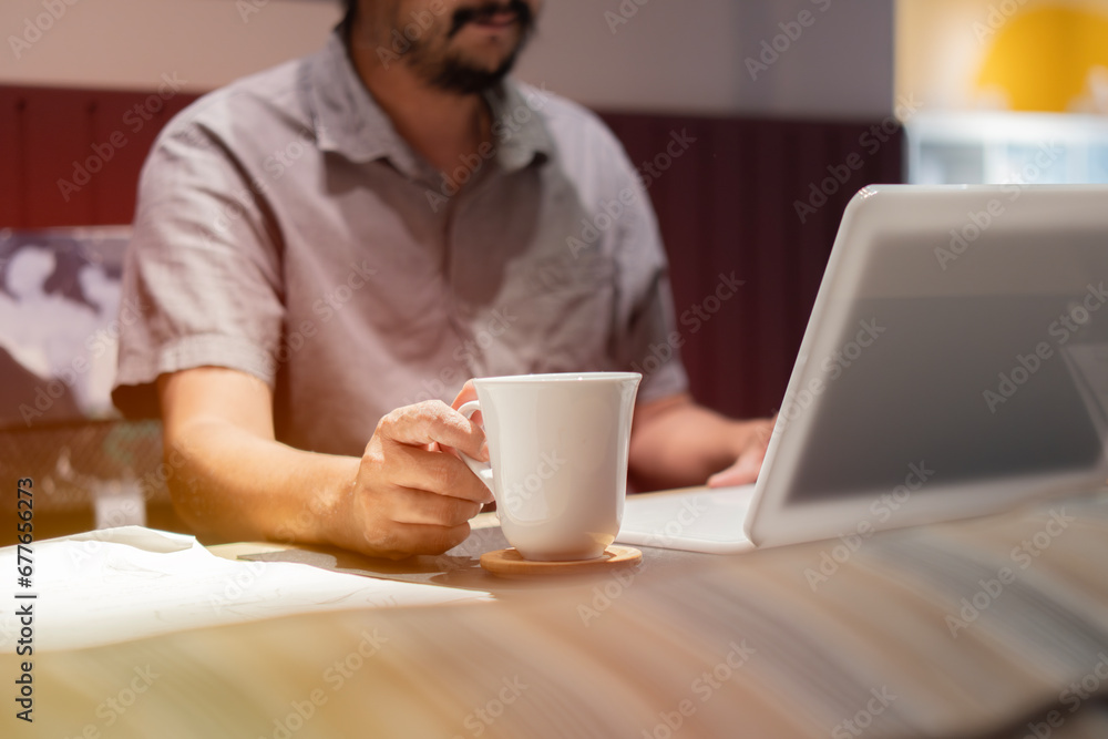 A happy businessman is sitting in a cafe, drinking coffee and watching a webinar on the laptop. A happy businessman is sitting in a cafe, drinking coffee and watching a webinar on the laptop.