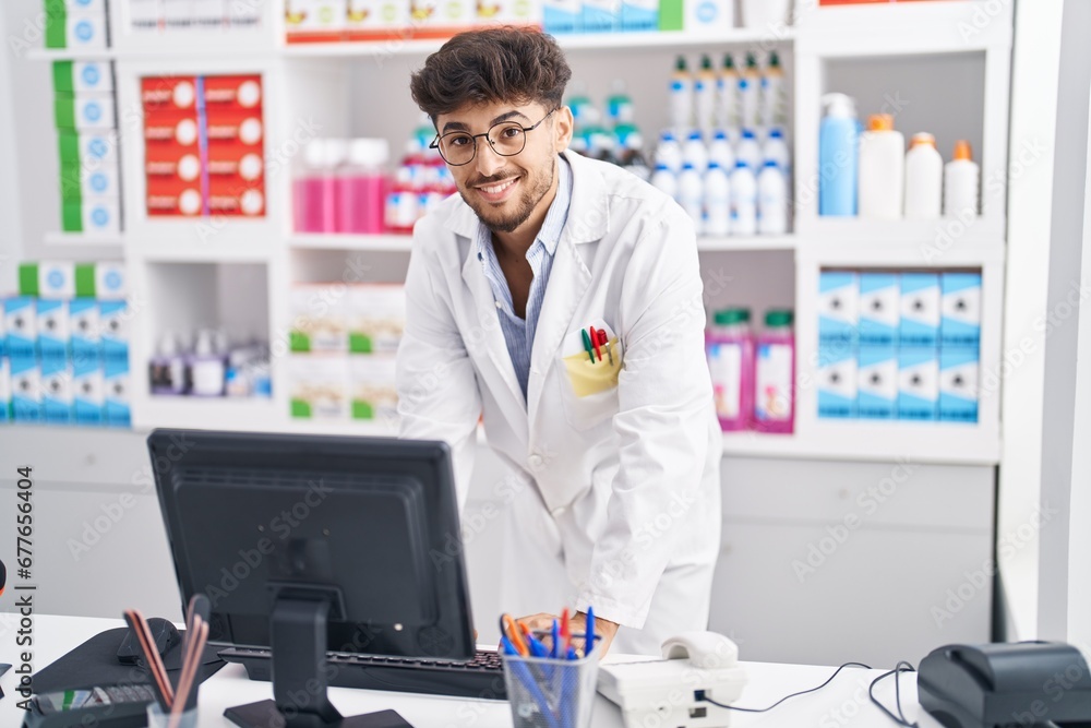 Young arab man pharmacist using computer working at pharmacy
