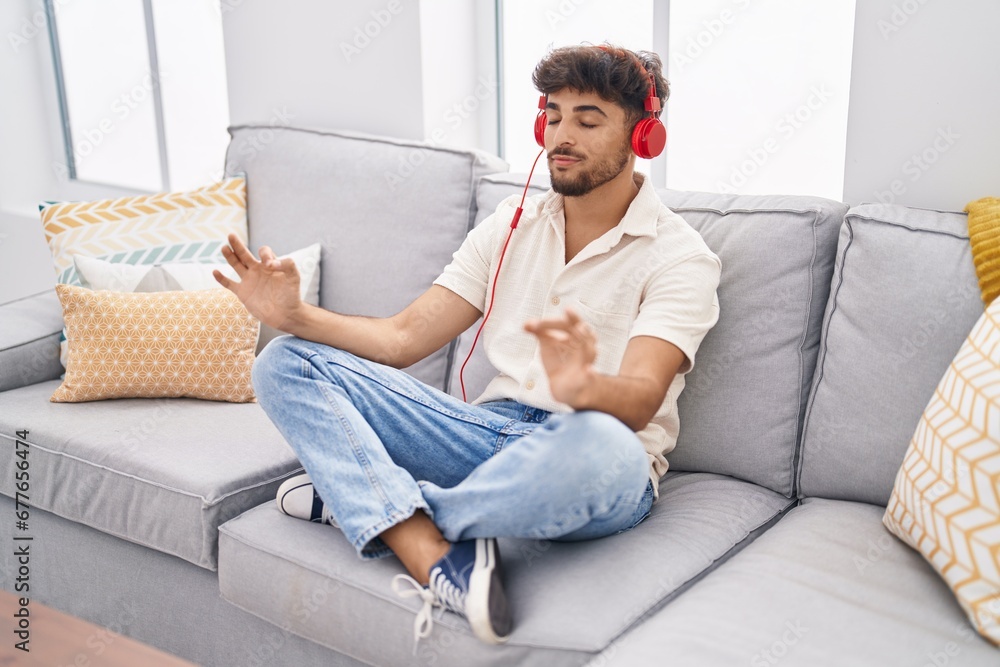 Young arab man doing yoga exercise sitting on sofa at home Young arab man doing yoga exercise sitting on sofa at home