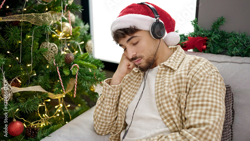 Young arab man sleeping on sofa by christmas tree at home