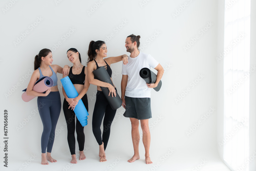 A group of female and male athletes stood and chatted amicably in the studio before beginning with the yoga class. A group of female and male athletes stood and chatted amicably in the studio before beginning with the yoga class.