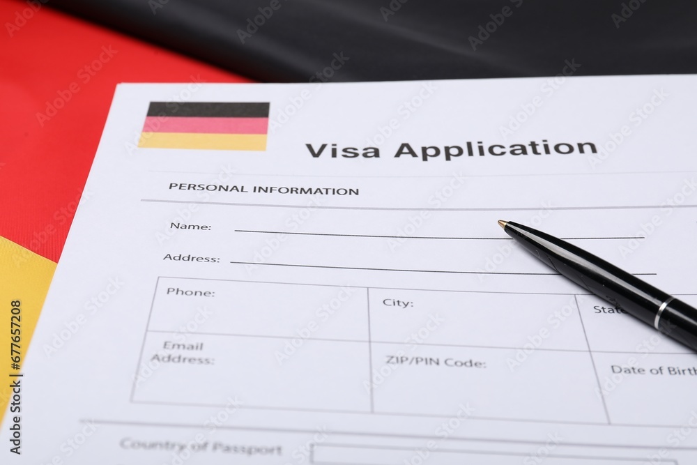 Immigration to Germany. Visa application form and pen on flag, closeup Immigration to Germany. Visa application form and pen on flag, closeup