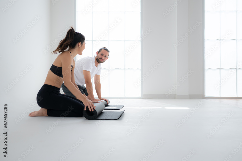 Obraz premium Couple doing yoga activities at home, Rolling up the yoga mat