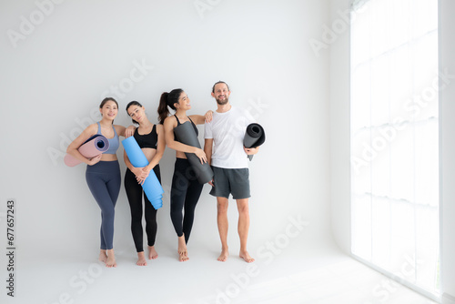 A group of female and male athletes stood and chatted amicably in the studio before beginning with the yoga class.