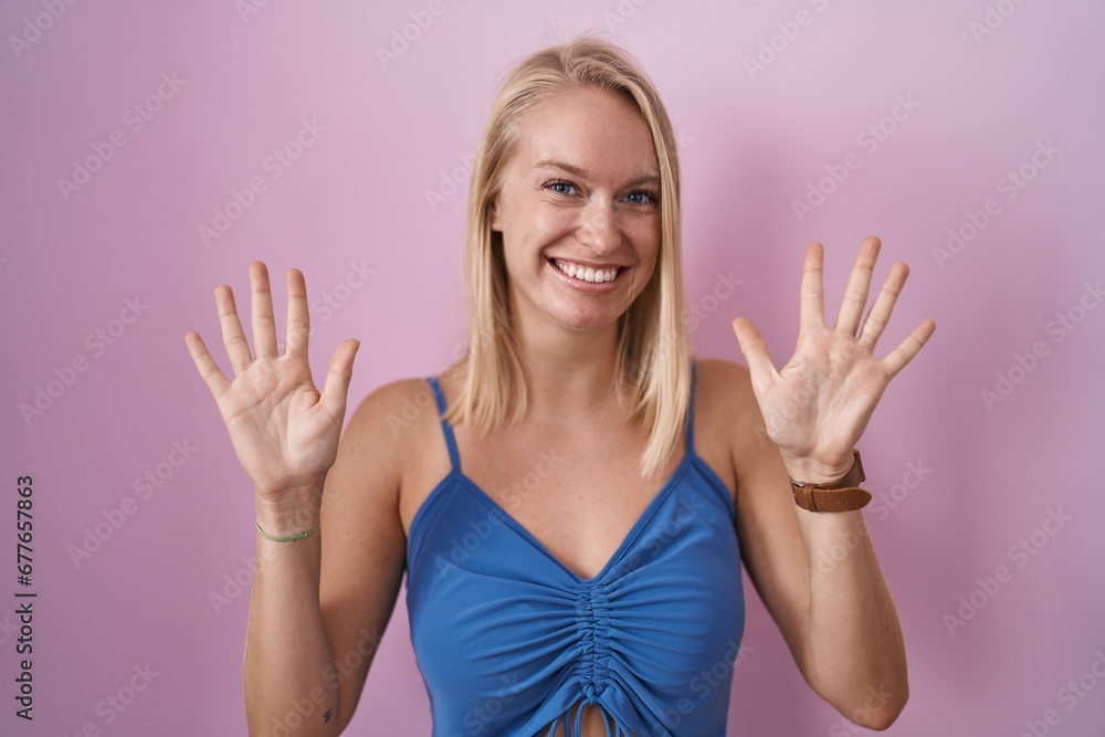 Young caucasian woman standing over pink background showing and pointing up with fingers number ten while smiling confident and happy. Young caucasian woman standing over pink background showing and pointing up with fingers number ten while smiling confident and happy.