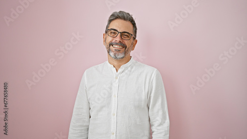 Принти на полотні Confident, grey-haired hispanic man flaunting a charming smile, wearing glasses,