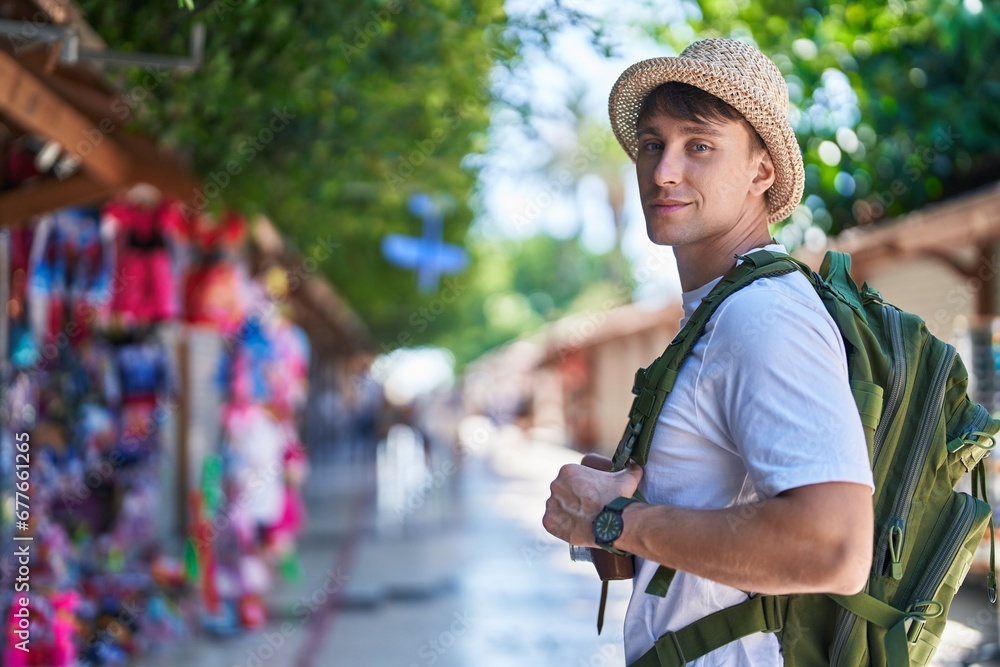 Young caucasian man tourist smiling confident doing heart gesture with hands at street market