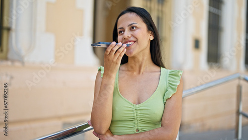 Young beautiful hispanic woman sending voice message with smartphone at street