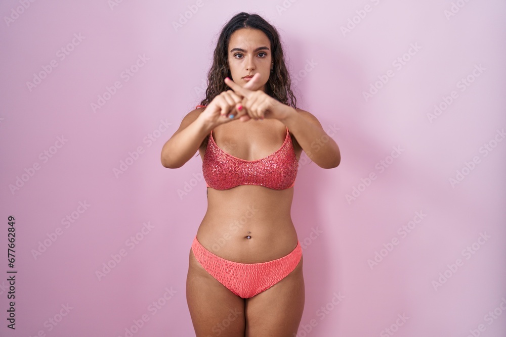 Young hispanic woman wearing lingerie over pink background rejection expression crossing fingers doing negative sign Young hispanic woman wearing lingerie over pink background rejection expression crossing fingers doing negative sign