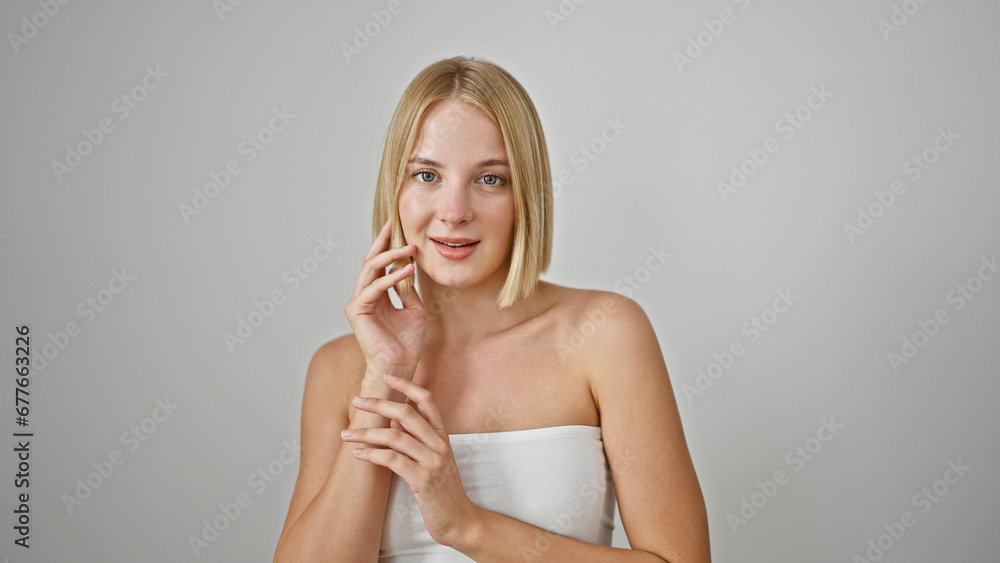 Young blonde woman smiling confident touching face over isolated white background Young blonde woman smiling confident touching face over isolated white background