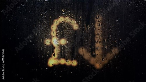Blurred glowing Turkey Lira sign made from light bulbs.The symbol of the national currency behind a rain-wet window with water drops in the night.Sign of economic crisis and business problems photo