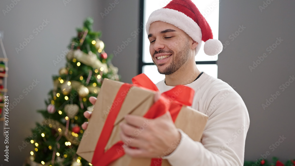 Young hispanic man smiling confident holding christmas gift at home Young hispanic man smiling confident holding christmas gift at home