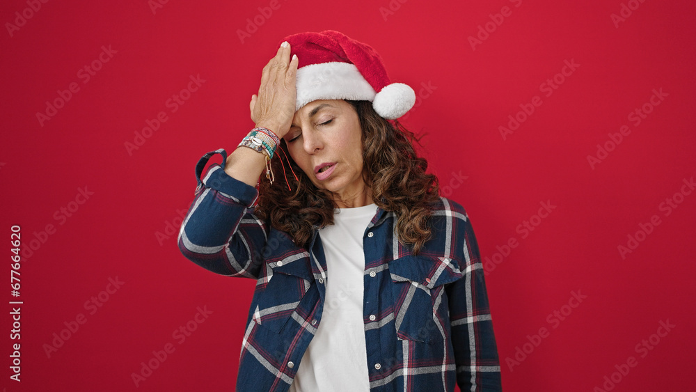 Middle age hispanic woman wearing christmas hat having headache over isolated red background Middle age hispanic woman wearing christmas hat having headache over isolated red background