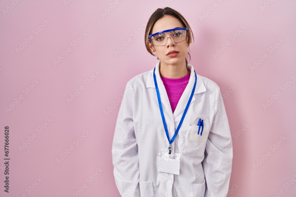 Hispanic woman wearing scientist uniform with serious expression on face. simple and natural looking at the camera. Hispanic woman wearing scientist uniform with serious expression on face. simple and natural looking at the camera.