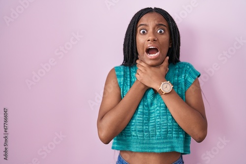 Young african american with braids standing over pink background shouting suffocate because painful strangle. health problem. asphyxiate and suicide concept.