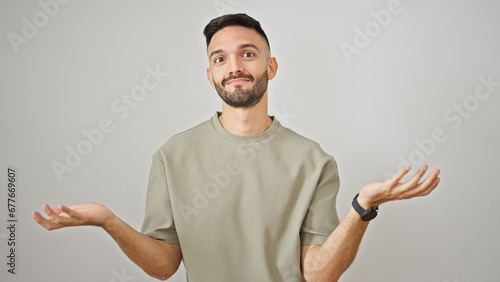 Obraz na płótnie Young hispanic man standing clueless over isolated white background