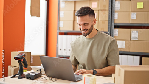 Young hispanic man ecommerce business worker using laptop smiling at office