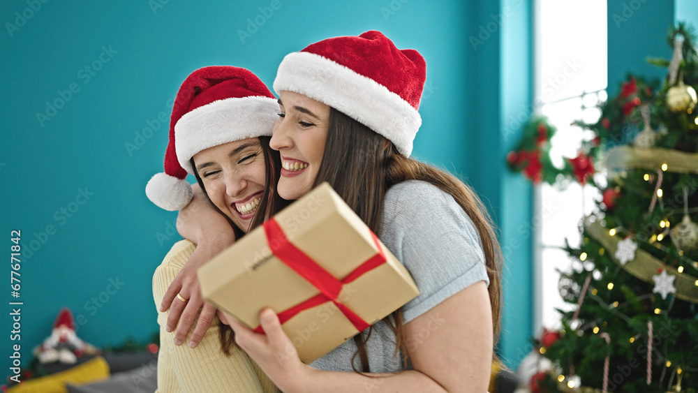 Two women surprising with christmas gift at home Two women surprising with christmas gift at home