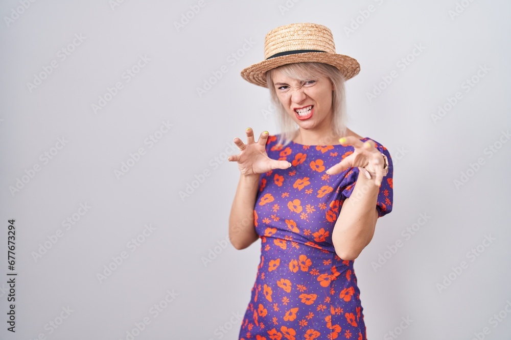 Young caucasian woman wearing flowers dress and summer hat smiling funny doing claw gesture as cat, aggressive and sexy expression Young caucasian woman wearing flowers dress and summer hat smiling funny doing claw gesture as cat, aggressive and sexy expression