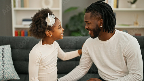 African american father and daughter sitting on sofa speaking at home
