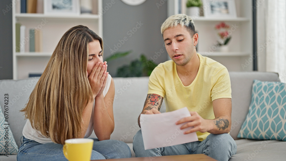 Beautiful couple reading document sitting on sofa looking upset at home Beautiful couple reading document sitting on sofa looking upset at home
