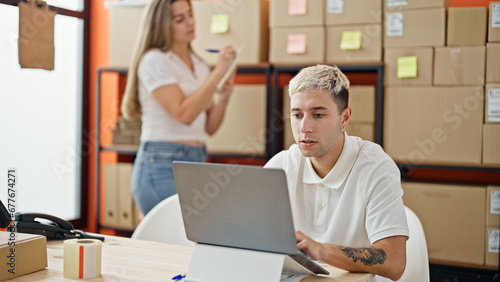 Two workers man and woman using laptop checking packages at office