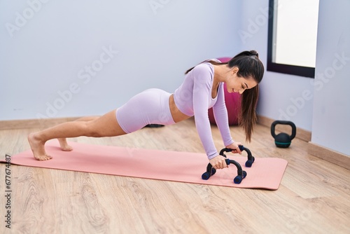 Young beautiful hispanic woman smiling confident training push up at sport center