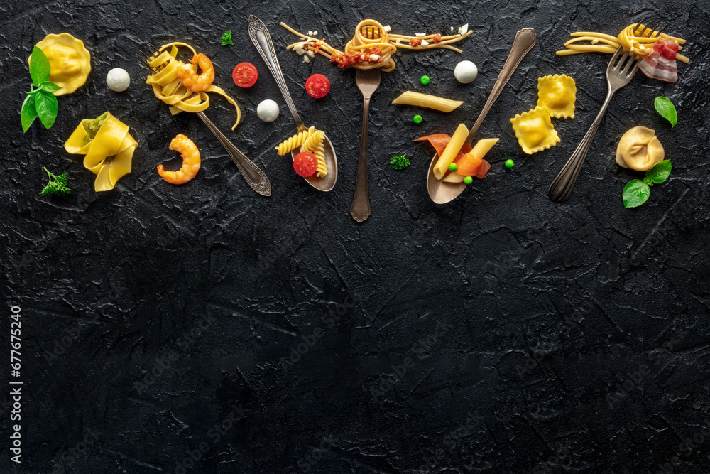 Various pasta forks. Spaghetti, fusilli, penne and other shapes of pasta, with sauce, overhead flat lay shot on a black slate background, with a place for text