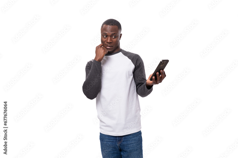 young american man with short haircut dressed in long-sleeved casual sweater holding smartphone young american man with short haircut dressed in long-sleeved casual sweater holding smartphone