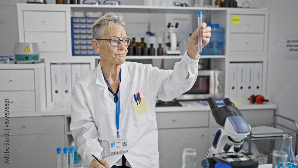 Grey-haired senior woman scientist working and measuring liquid in test tube in indoor laboratory, meticulously ensuring safety and precision in medical research Grey-haired senior woman scientist working and measuring liquid in test tube in indoor laboratory, meticulously ensuring safety and precision in medical research