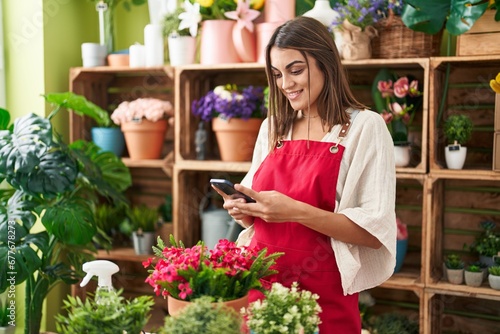 Young beautiful hispanic woman florist smiling confident using smartphone at flower shop