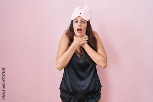 Young brunette woman wearing sleep mask and pyjama shouting and suffocate because painful strangle. health problem. asphyxiate and suicide concept.