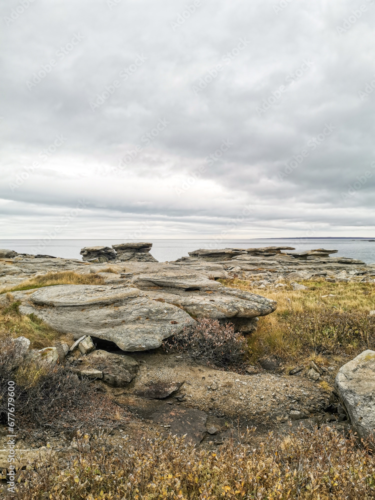 The shore of red stones next to the rocks are Two Brothers on the Fishing Peninsula. The picturesque shore of the harsh Barents Sea. The North of Russia. The Kola Peninsula. The Arctic