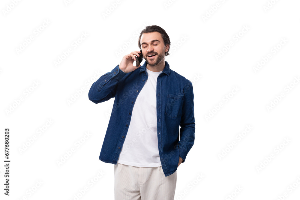 handsome young brunette man in a denim shirt chatting on the phone on a white background handsome young brunette man in a denim shirt chatting on the phone on a white background