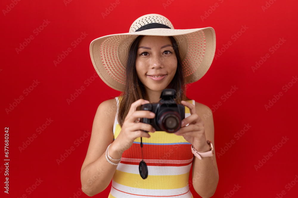 Middle age chinese woman using reflex camera wearing summer hat smiling with a happy and cool smile on face. showing teeth. Middle age chinese woman using reflex camera wearing summer hat smiling with a happy and cool smile on face. showing teeth.