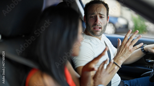 Beautiful couple sitting on car arguing at street