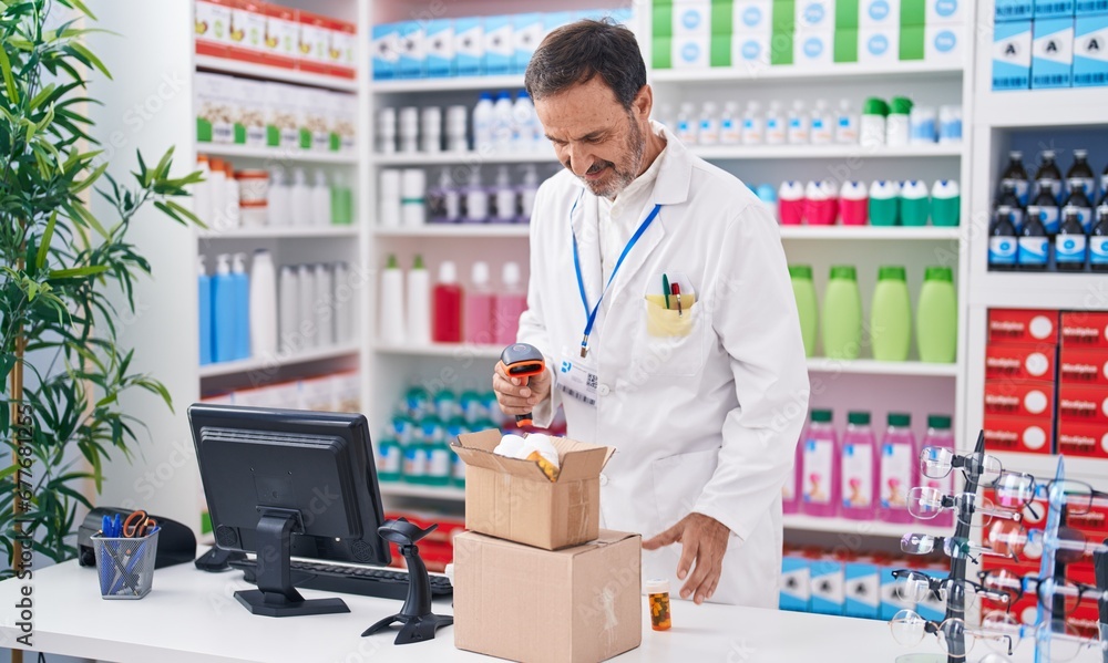 Middle age man pharmacist scanning pills bottle at pharmacy