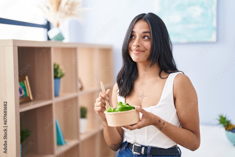Brunette woman eating a salad at home smiling looking to the side and staring away thinking. Brunette woman eating a salad at home smiling looking to the side and staring away thinking.