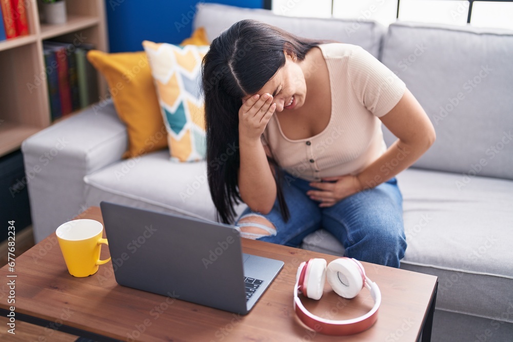 Young beautiful hispanic woman suffering for head and stomach ache at home Young beautiful hispanic woman suffering for head and stomach ache at home