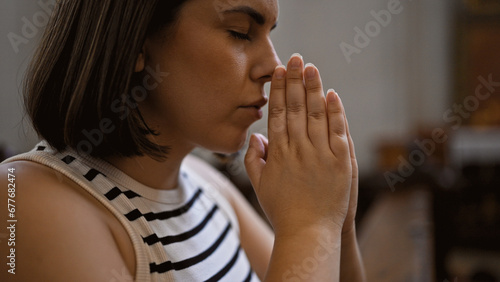 Young beautiful hispanic woman praying on a church bench at Augustinian Church in Vienna