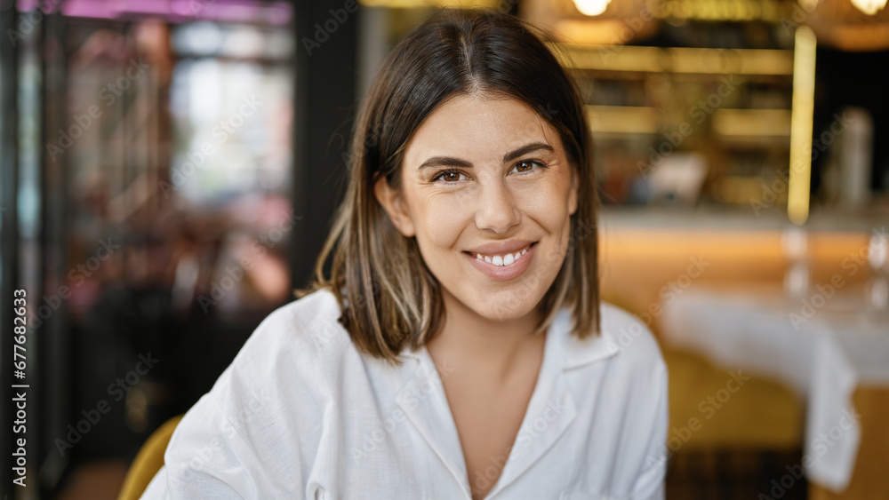 Young beautiful hispanic woman smiling happy sitting on the table at the restaurant Young beautiful hispanic woman smiling happy sitting on the table at the restaurant