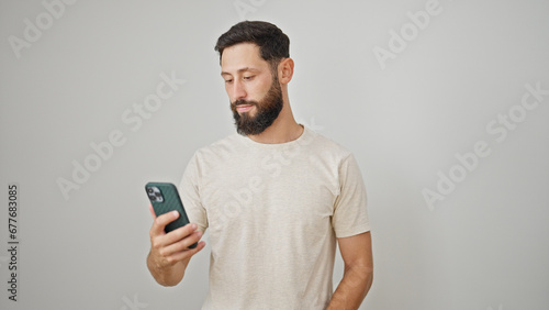 Young hispanic man using smartphone and earphones over isolated white background