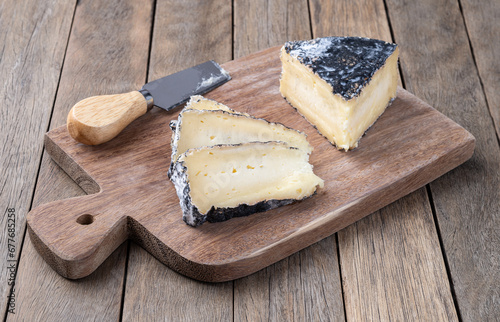 Charcoal aged cheese with slices over wooden table