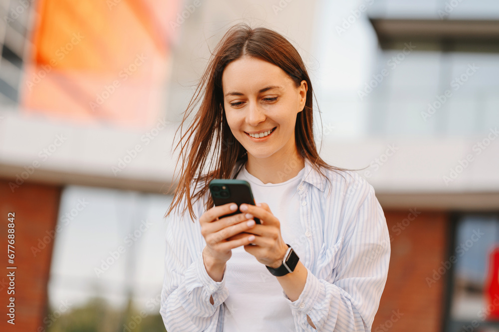 Happy young woman reading good news and looking at smartphone.