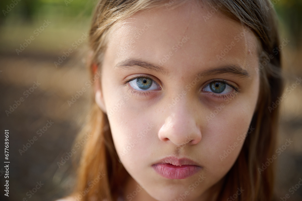 Fototapeta premium Portrait of sad young girl in the autumn park in sunny bright day. Close up.