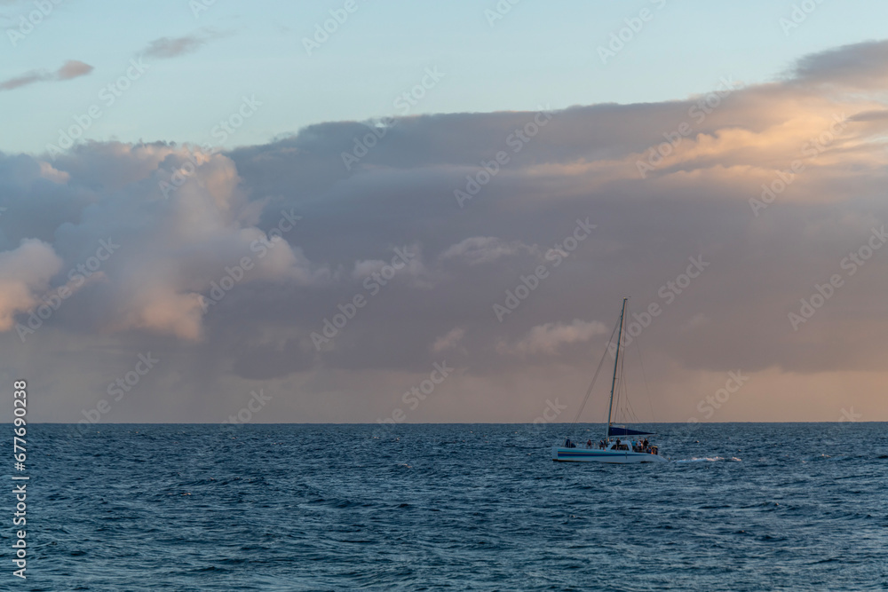 Ocean scene with rain clouds above and a boat on the water in the Pacific Ocean off of Kauai, Hawaii, United States.

