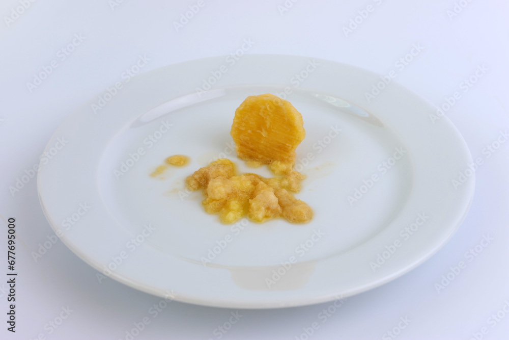 A miniature grater and grated potatoes on a white plate. A miniature grater and grated potatoes on a white plate.